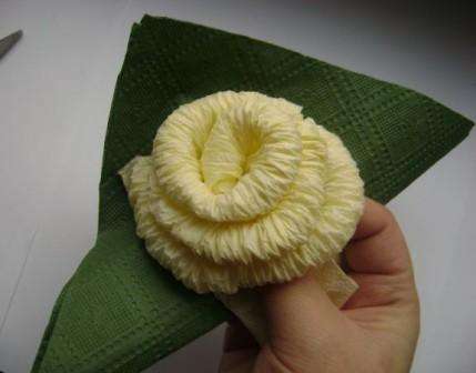Etter det, ta grønne servietter for å lage blomsterblader. Brett serviettene inn i en trekant og pakk den inn ved foten av knoppen. Du bør få et blad. Lag tre av disse bladene til en rose.